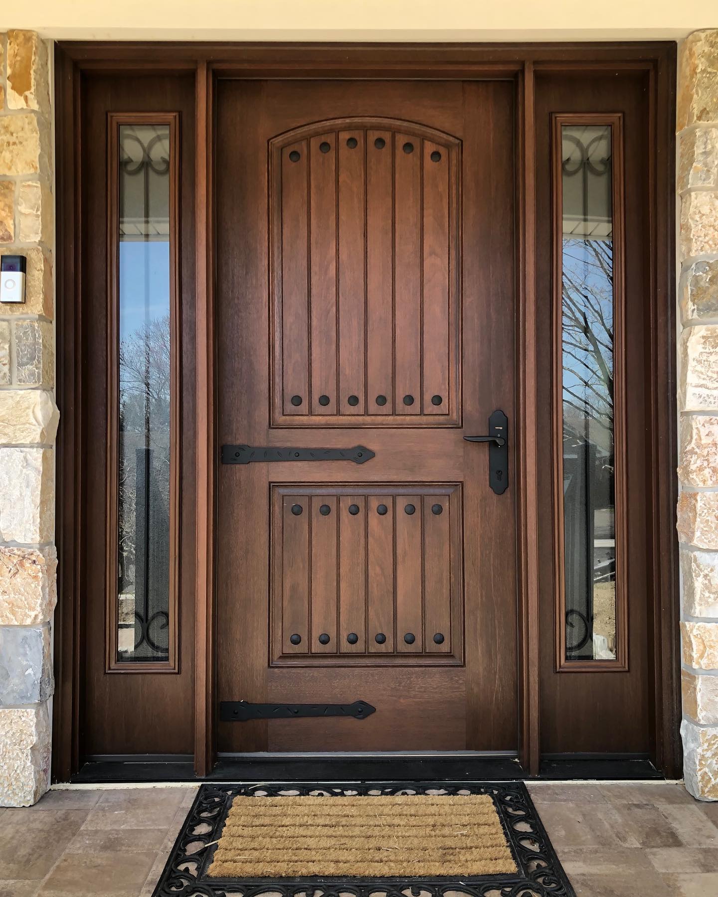 Rustic arched entry door with black iron hardware